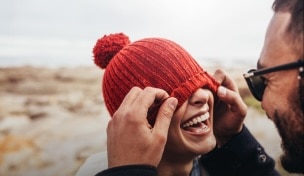 Femeie cu rucsac, însoțită într-o drumeție pe un drum de țară și zâmbind