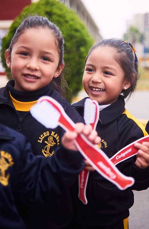 Smiling girls holding colgate toothbrushes Smiling girls holding colgate toothbrushes